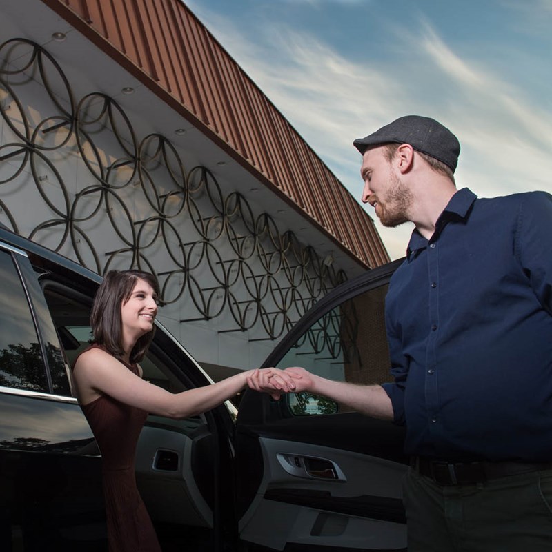 People stepping out of their parked car in front of the building
