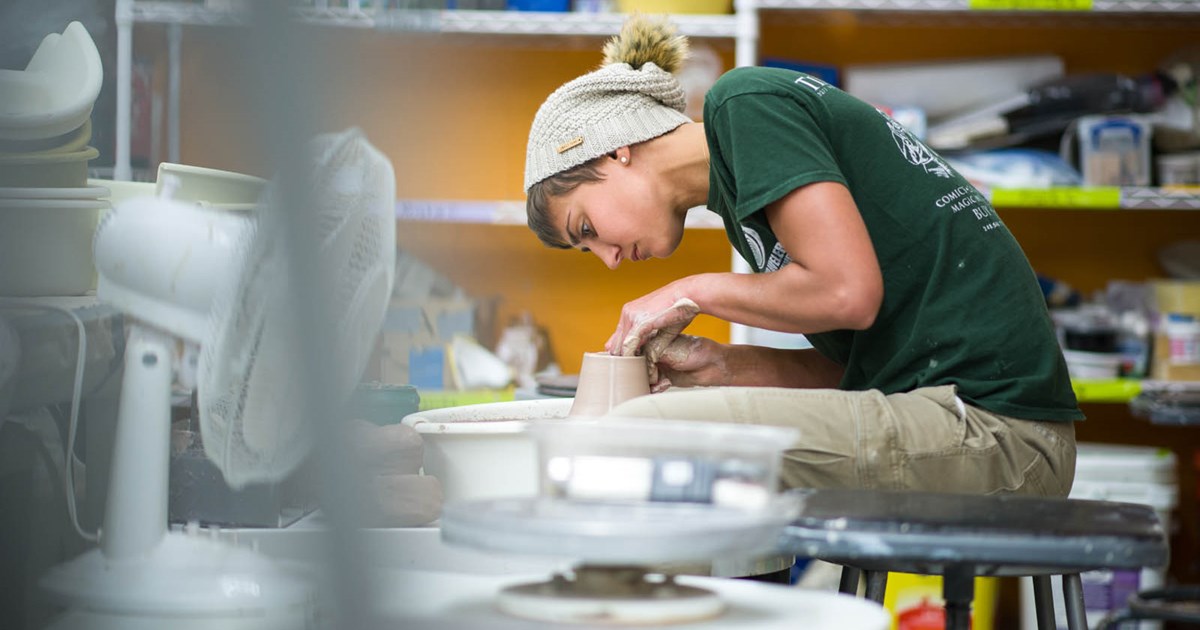 student molding clay in studio school