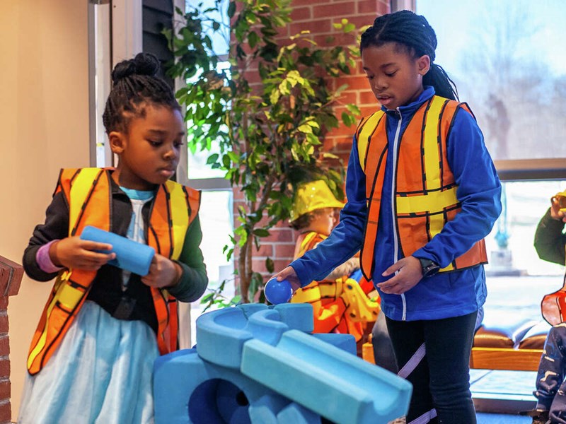 Children playing with construction themed toys in exhibit