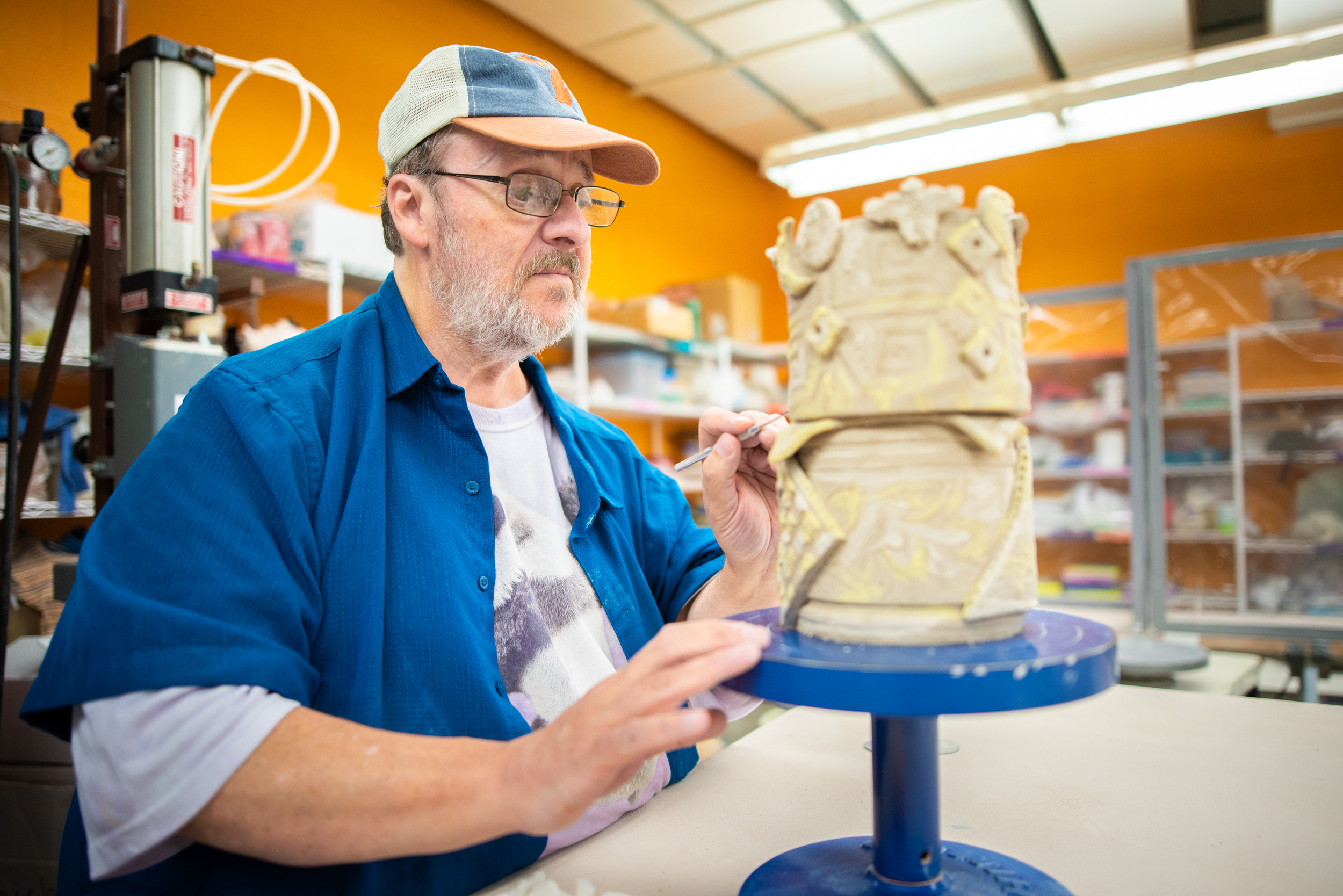A man doing finishing touches with a fine brush on an intricate ceramic