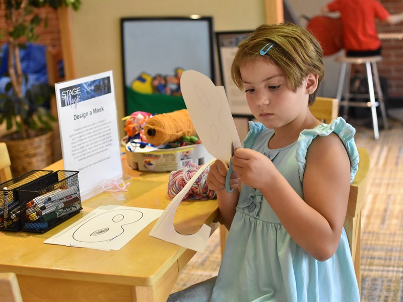 A child cutting out a paper mask.
